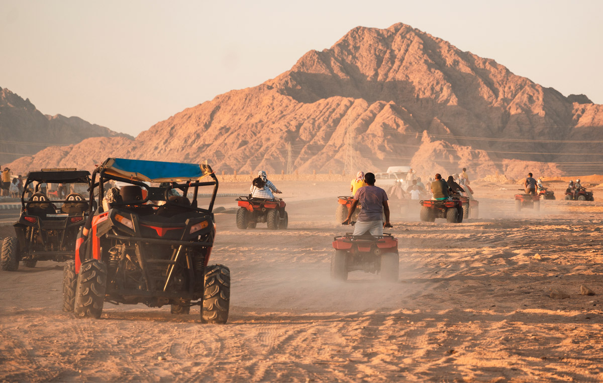 A powerful vehicle racing through sunlit sand with wild desert energy.