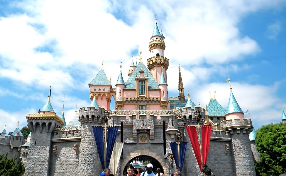 Iconic Disney castle under a clear blue sky with visitors below.