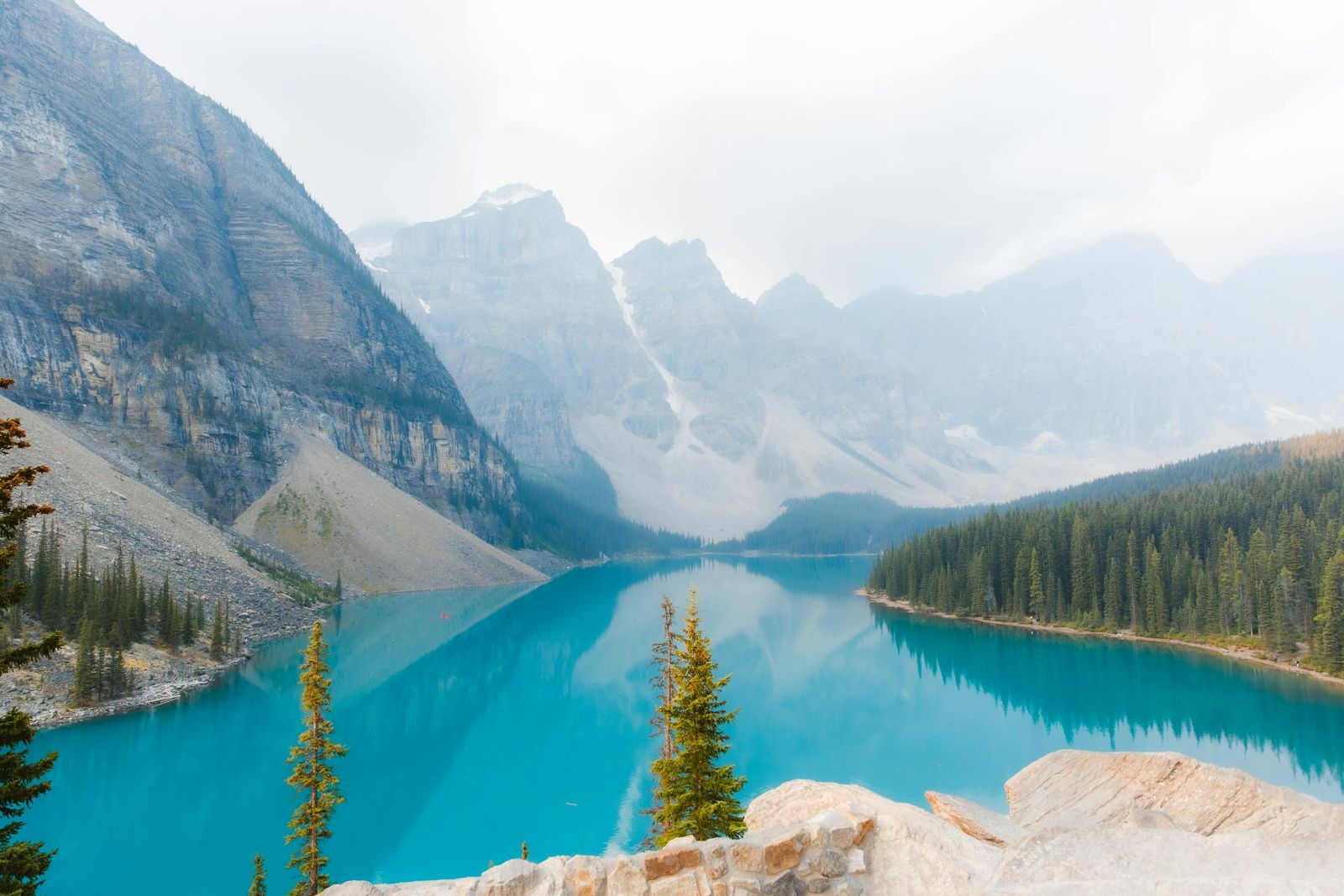 Turquoise lake surrounded by majestic mountains under a peaceful sky.