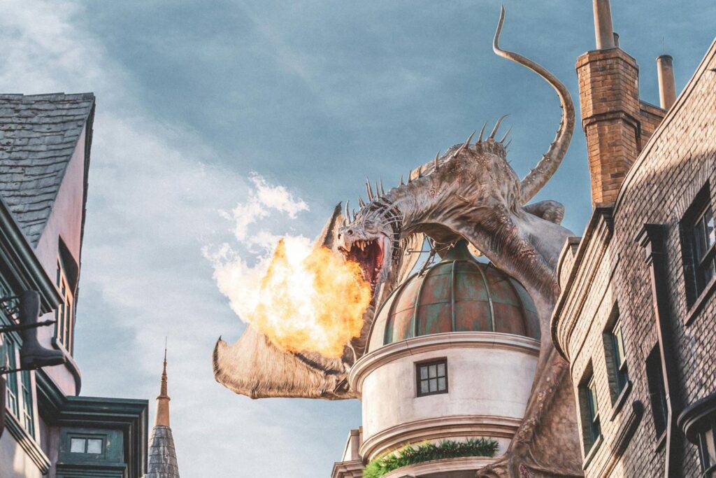 A large dragon statue breathing fire above a themed building.