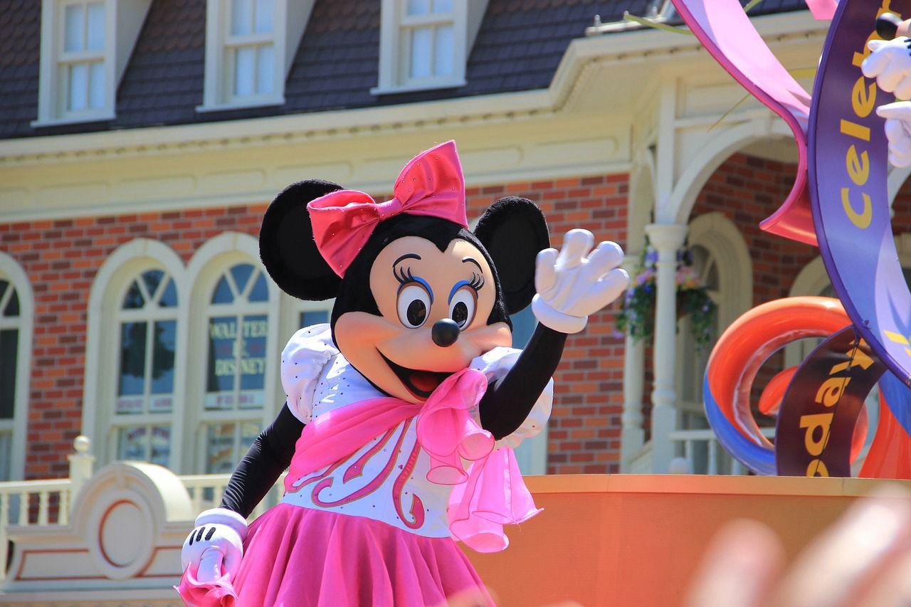 A performer in a colorful costume smiling and waving during a festive event.