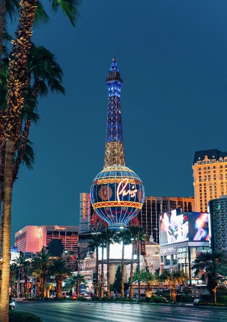Las Vegas Strip at night with illuminated Eiffel Tower replica and city lights.