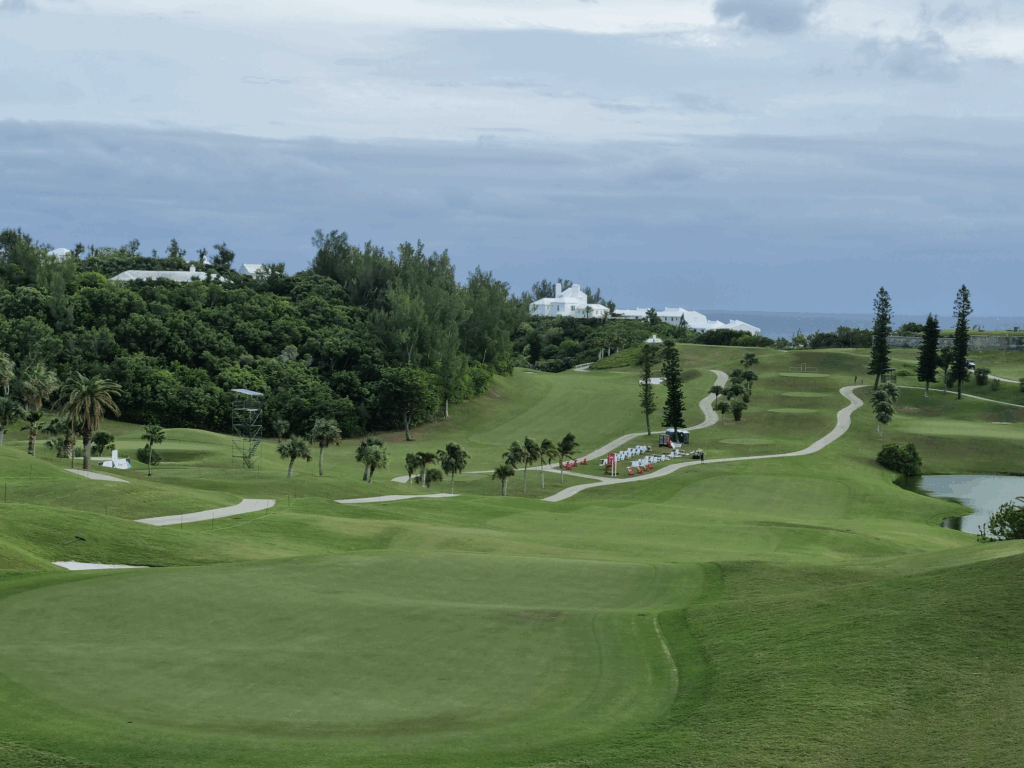 Rolling green golf course overlooking the ocean with palm trees and winding paths