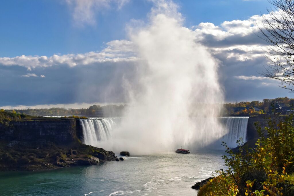 Large waterfall with mist rising above river and cliffs.